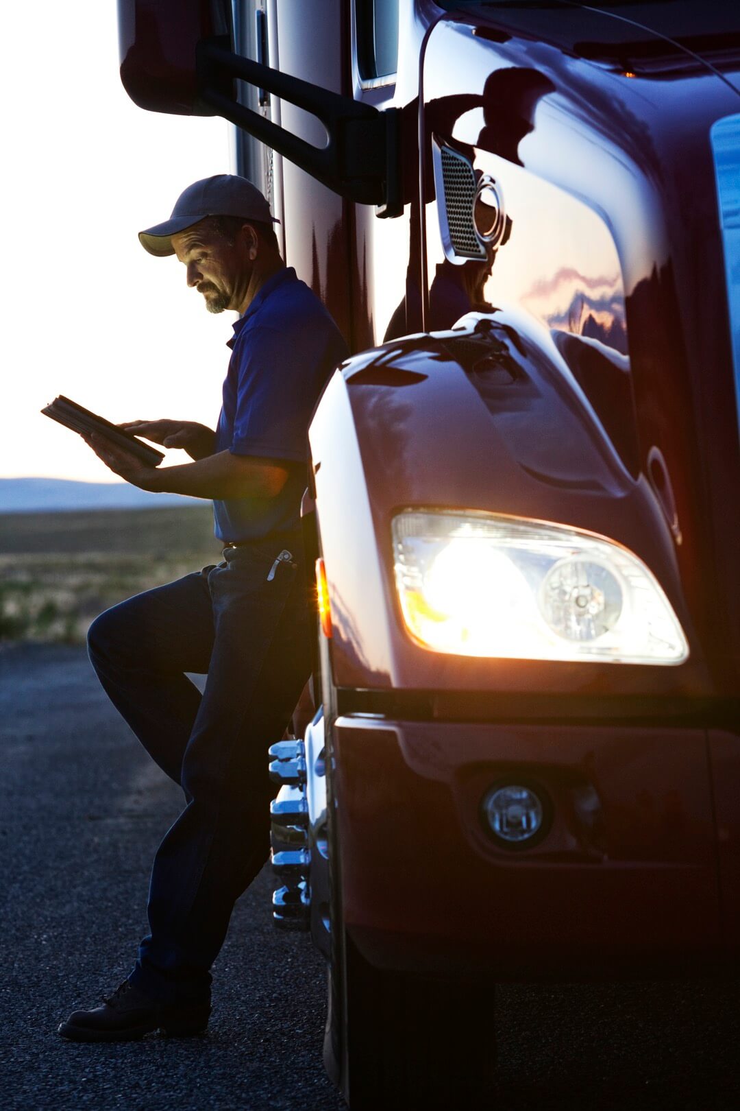 Conducteur de camion vérifiant le journal de son ordinateur portable en se tenant à côté de la cabine de son camion commercial.