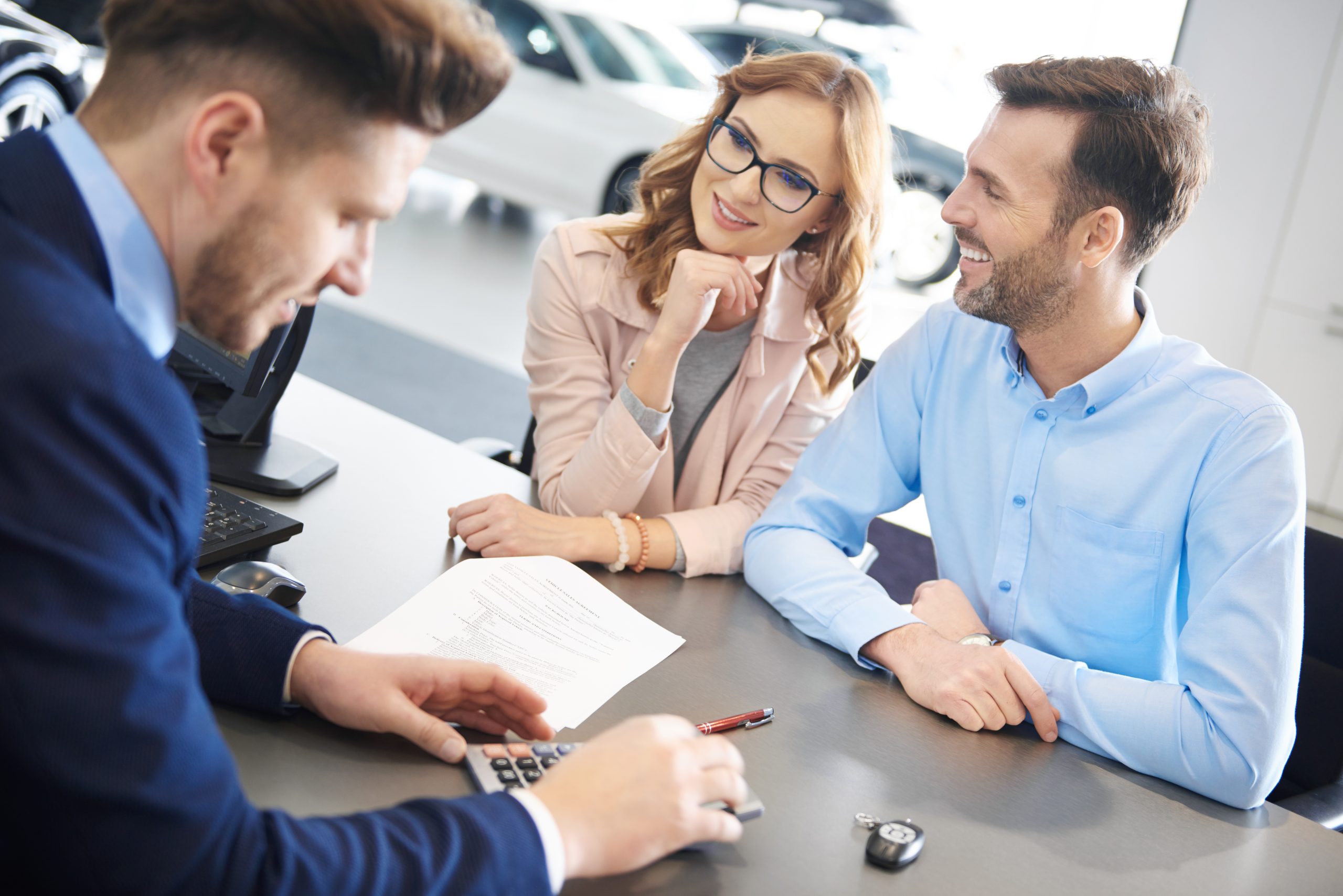 Un vendeur automobile calculant les frais de voiture à ses clients.
